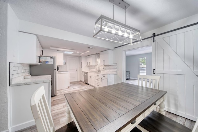 dining room with a barn door and light wood finished floors