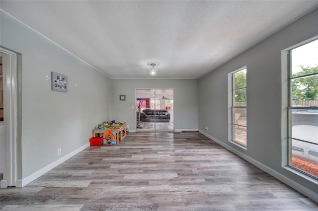 playroom featuring a textured ceiling, wood finished floors, and baseboards