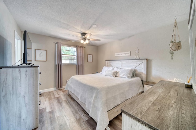 bedroom featuring a textured ceiling, light wood-style floors, and a ceiling fan