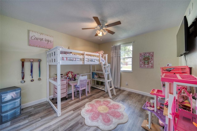 bedroom with baseboards, wood finished floors, and a textured ceiling