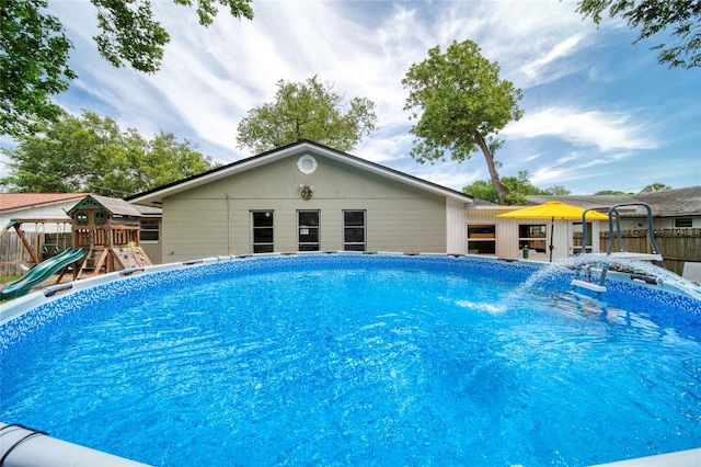 view of pool featuring fence, a playground, a jacuzzi, and a fenced in pool