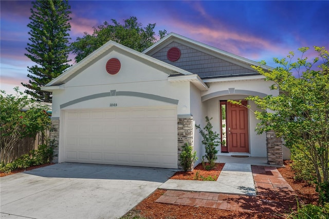 view of front of house with an attached garage, stucco siding, driveway, and stone siding