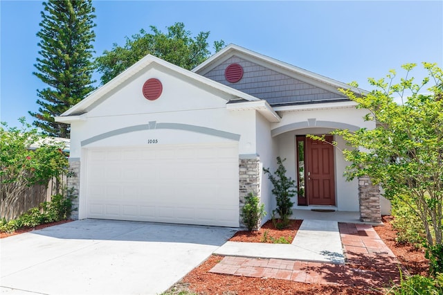 view of front of house with concrete driveway, stucco siding, an attached garage, and stone siding