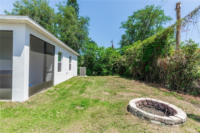 view of yard with central AC unit and a fire pit