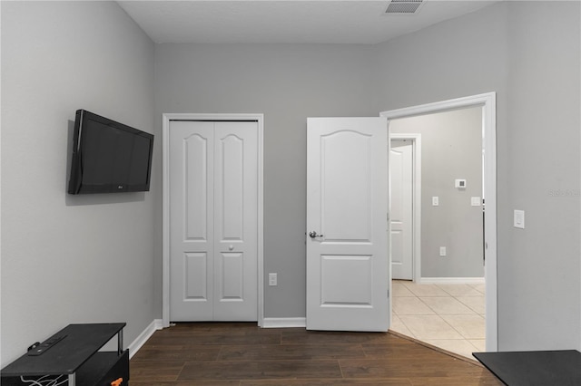 unfurnished bedroom with dark wood-style flooring, baseboards, visible vents, and a closet