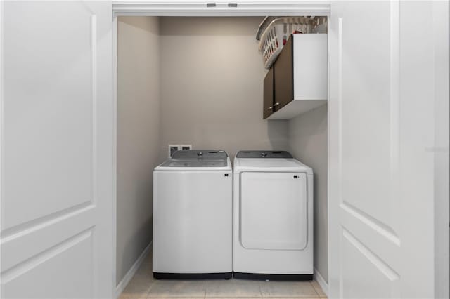 washroom with baseboards, cabinet space, light tile patterned floors, and washing machine and clothes dryer