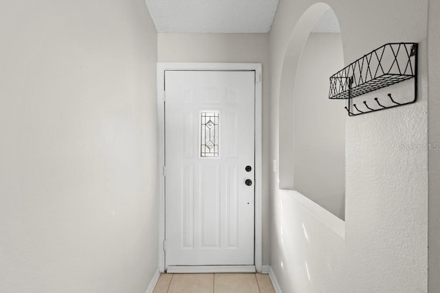 entryway featuring light tile patterned flooring, baseboards, and arched walkways