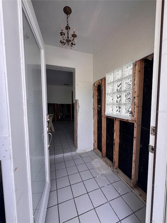 855 Boca Ciega Isle Dr, St Pete Beach, FL 33706 - hall featuring an inviting chandelier, a textured wall, and light tile patterned flooring