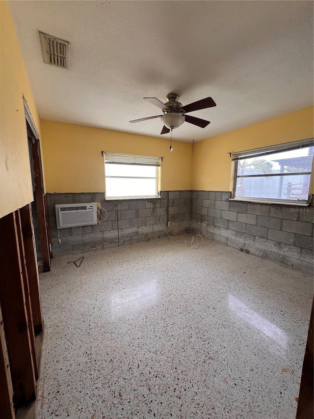 855 Boca Ciega Isle Dr, St Pete Beach, FL 33706 - empty room with a wall unit AC, a ceiling fan, visible vents, wainscoting, and concrete block wall
