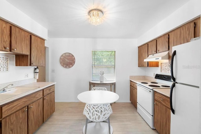 kitchen featuring brown cabinets, white appliances, under cabinet range hood, light countertops, and a chandelier