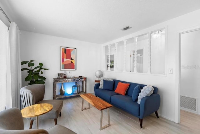 living area featuring baseboards, light wood-style floors, and visible vents