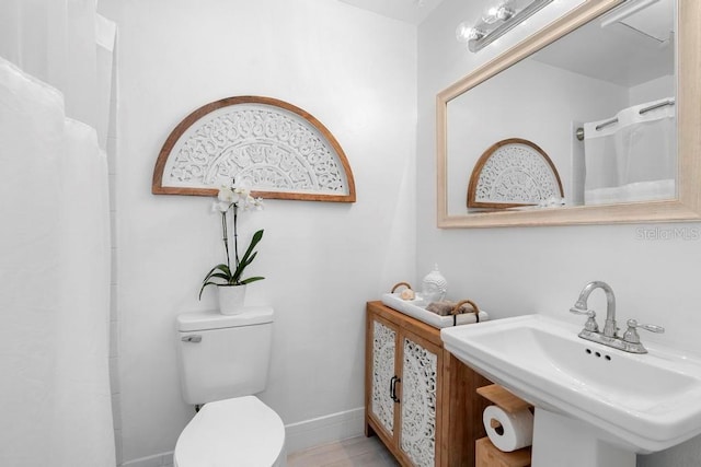full bathroom with a sink, toilet, and a shower with shower curtain