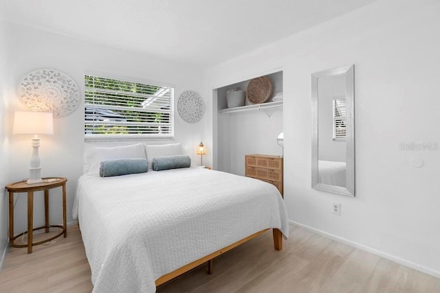 bedroom with a closet, wood finished floors, and baseboards