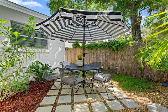 view of patio featuring outdoor dining area and fence