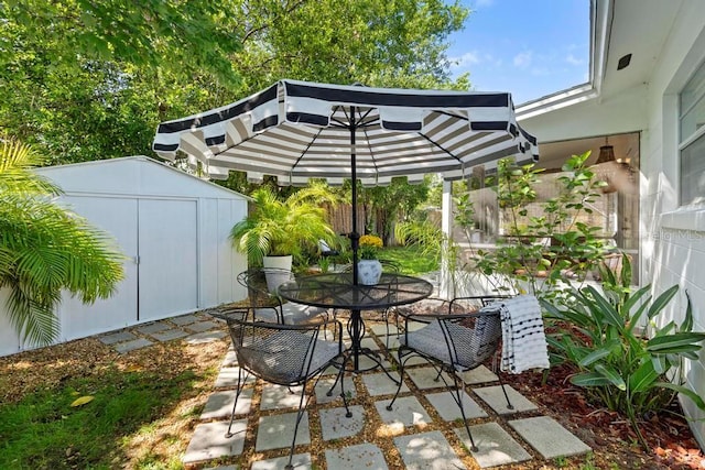 view of patio / terrace with an outdoor structure, fence, outdoor dining space, and a storage unit