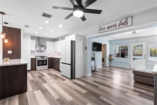 2824 Oak Lea Dr, South Daytona, FL 32119 - kitchen with visible vents, stainless steel gas stove, light countertops, freestanding refrigerator, and wall chimney exhaust hood