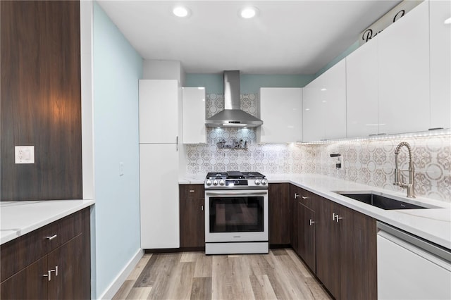 2824 Oak Lea Dr, South Daytona, FL 32119 - kitchen featuring gas range, white dishwasher, a sink, white cabinets, and wall chimney exhaust hood