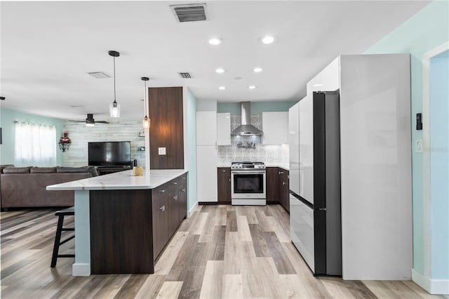 2824 Oak Lea Dr, South Daytona, FL 32119 - kitchen featuring wall chimney range hood, dark brown cabinets, freestanding refrigerator, stainless steel range with gas cooktop, and modern cabinets