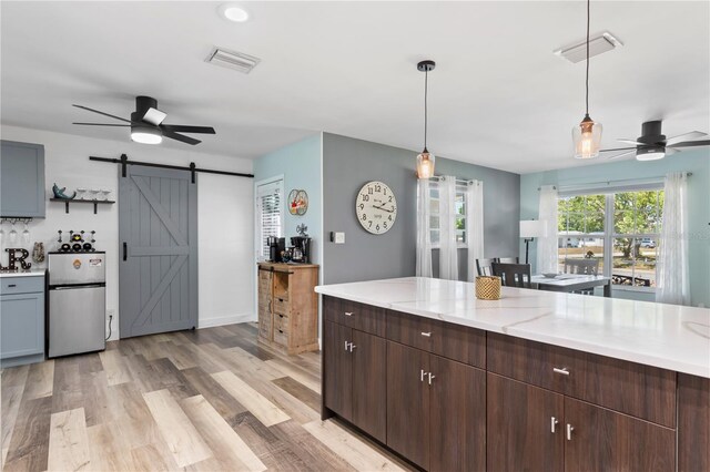 2824 Oak Lea Dr, South Daytona, FL 32119 - kitchen featuring visible vents, freestanding refrigerator, ceiling fan, a barn door, and light wood-style flooring