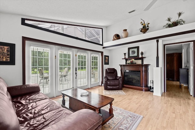 30 Reflections Village Dr, Ormond Beach, FL 32174 - living room featuring a glass covered fireplace, light wood-type flooring, a textured ceiling, and visible vents