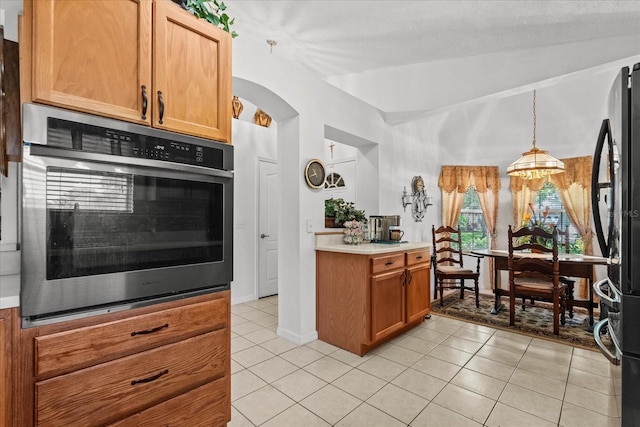 30 Reflections Village Dr, Ormond Beach, FL 32174 - kitchen with vaulted ceiling, light tile patterned floors, light countertops, freestanding refrigerator, and stainless steel oven