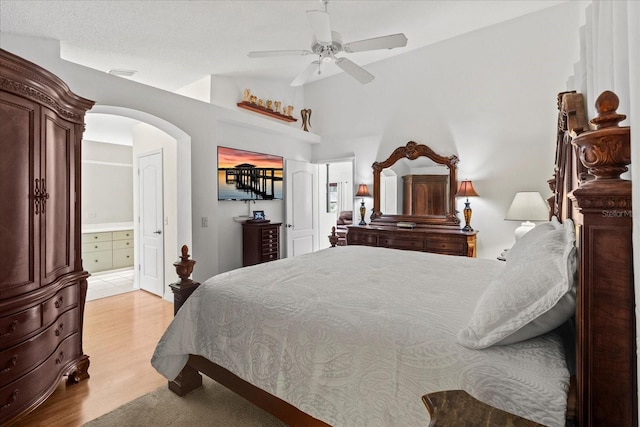 30 Reflections Village Dr, Ormond Beach, FL 32174 - bedroom with ensuite bath, arched walkways, light wood-style flooring, a ceiling fan, and vaulted ceiling