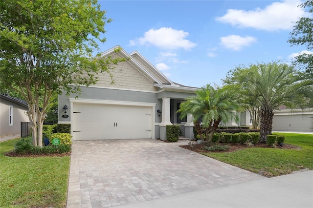 view of front of house featuring decorative driveway, an attached garage, a front yard, and stucco siding