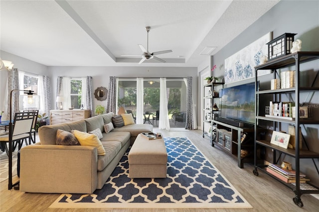 living room featuring a tray ceiling, a ceiling fan, and wood finished floors