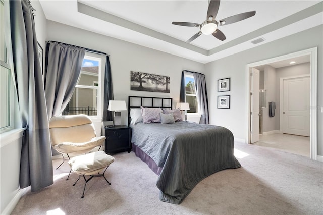 bedroom featuring ceiling fan, carpet, baseboards, a tray ceiling, and visible vents