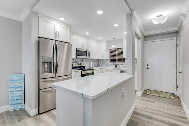 kitchen with a kitchen island, light stone countertops, baseboards, ornamental molding, and stainless steel appliances