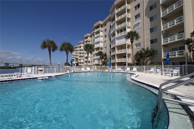 community pool with a patio and fence