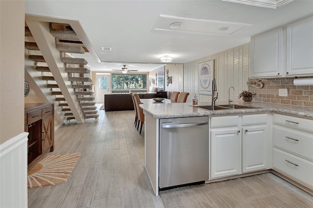 kitchen with dishwasher, light wood finished floors, a sink, open floor plan, and white cabinets