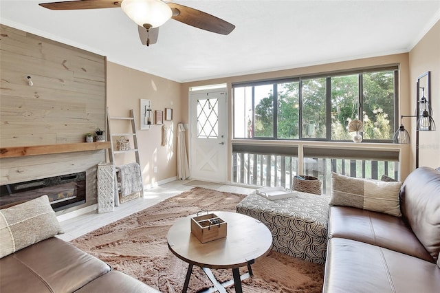 living room featuring baseboards, ornamental molding, a healthy amount of sunlight, and ceiling fan