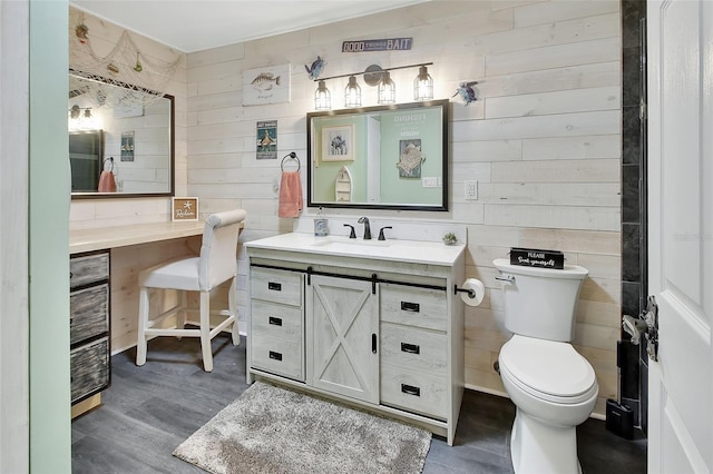 bathroom featuring toilet, wood walls, wood finished floors, and vanity