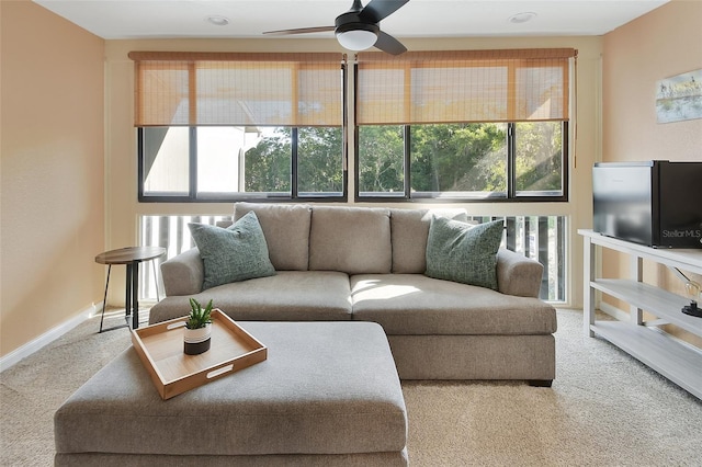 carpeted living area featuring a ceiling fan, baseboards, and a healthy amount of sunlight
