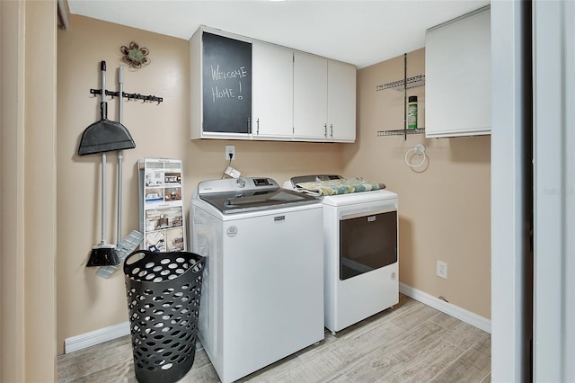 laundry room featuring baseboards, light wood-style floors, separate washer and dryer, and cabinet space