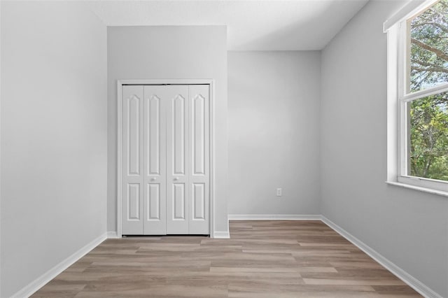 15733 Green Point Ct, Clermont, FL 34714 - unfurnished bedroom with light wood finished floors, a closet, baseboards, and multiple windows