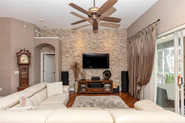 living room featuring a ceiling fan, arched walkways, and wood finished floors