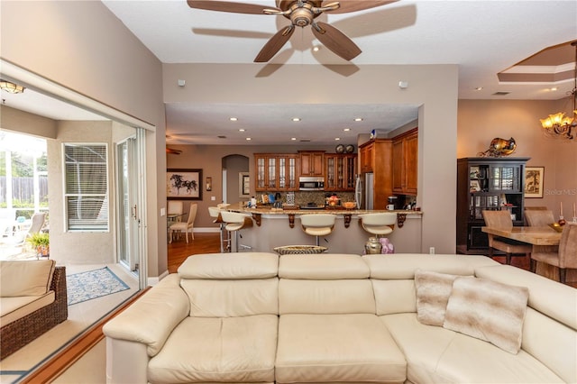 living room with recessed lighting, wood finished floors, and ceiling fan with notable chandelier