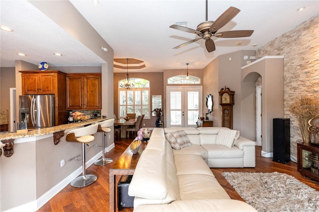 living room featuring french doors, arched walkways, ceiling fan with notable chandelier, and dark wood finished floors