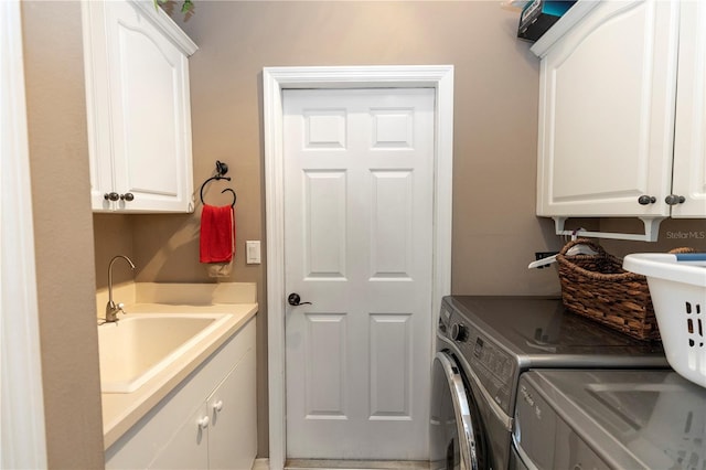clothes washing area featuring cabinet space, washer and clothes dryer, and a sink