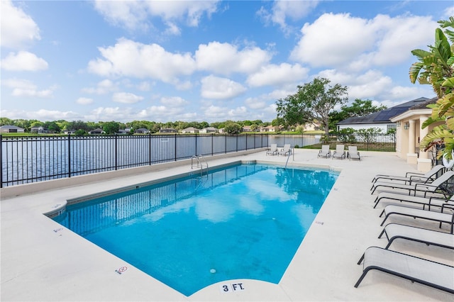 community pool featuring a patio, fence, and a water view