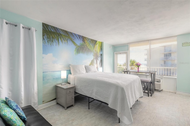 bedroom with baseboards, a wall mounted AC, and light wood-type flooring