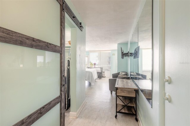 hall with light wood-type flooring and a barn door