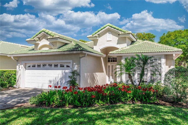 mediterranean / spanish-style home with an attached garage, stucco siding, driveway, and a tile roof