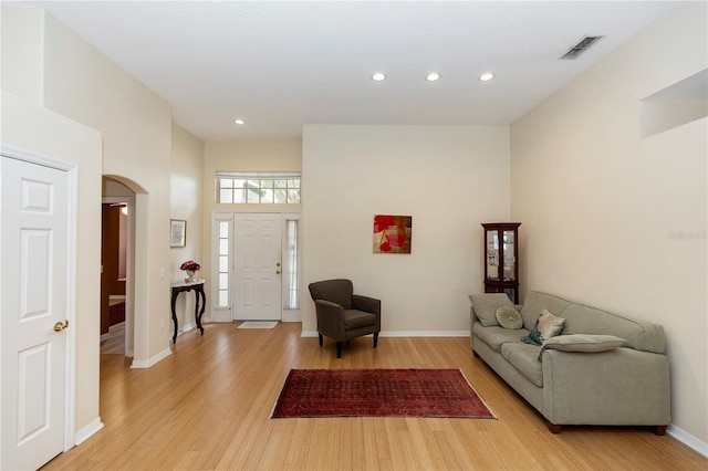 living area featuring visible vents, baseboards, light wood-type flooring, recessed lighting, and arched walkways