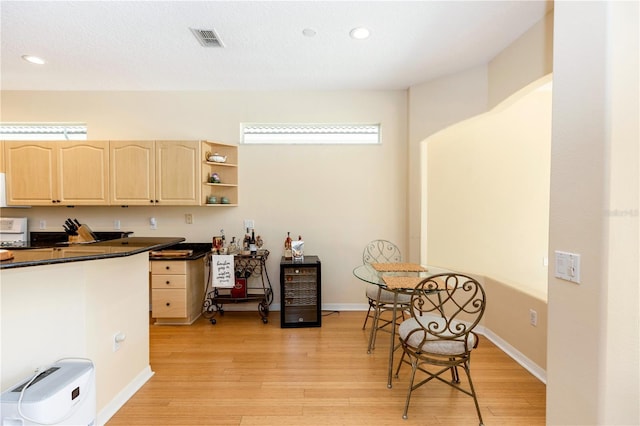 kitchen featuring light brown cabinetry, dark countertops, light wood-style floors, recessed lighting, and visible vents