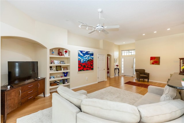 living room featuring light wood-style floors, baseboards, recessed lighting, built in shelves, and a ceiling fan