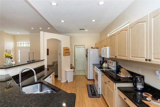 kitchen with visible vents, light brown cabinetry, white appliances, a sink, and light wood-style flooring