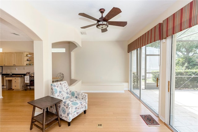 sitting room featuring arched walkways, ceiling fan, visible vents, and light wood-type flooring